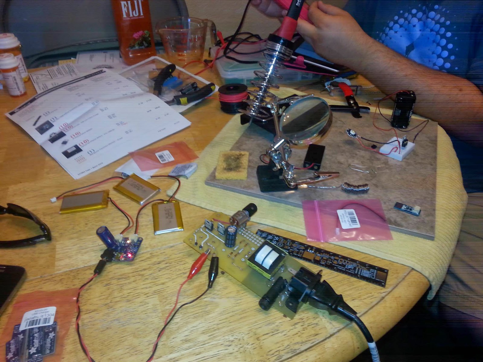 Prototyping at the kitchen table which is covered in components and tools.
